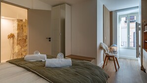 Une chambre à coucher avec un lit, une chaise, une armoire et une vue sur l’extérieur.
