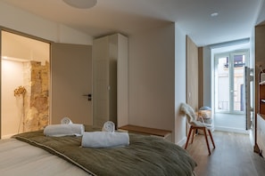 Une chambre à coucher avec un lit, une chaise, une armoire et une vue sur l’extérieur.
