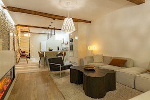 Un salon moderne avec une cheminée, un canapé d’angle, une table basse et un coin repas avec des chaises.