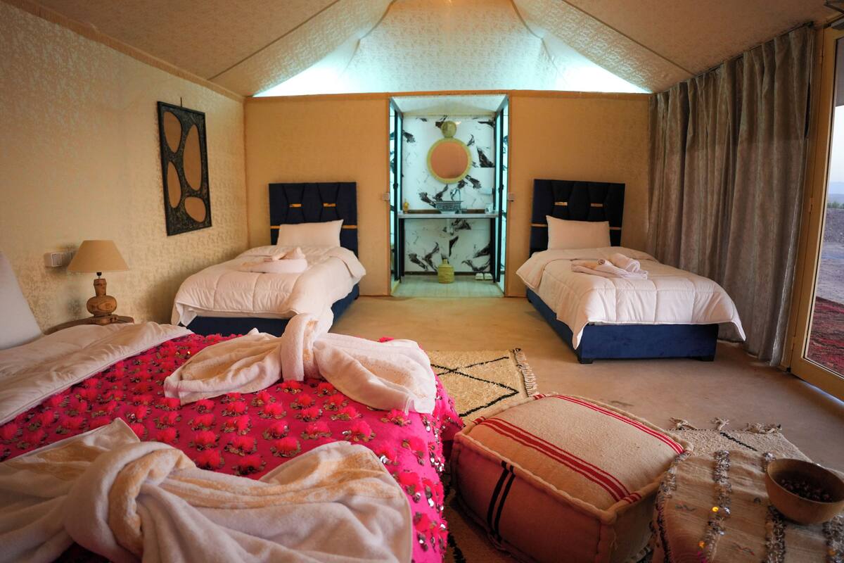 A hotel room with two beds, a large window, and a view of the outdoors.