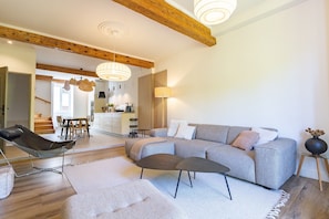 A modern living room with a sofa, a chair, and a coffee table. There is a staircase leading to another room.