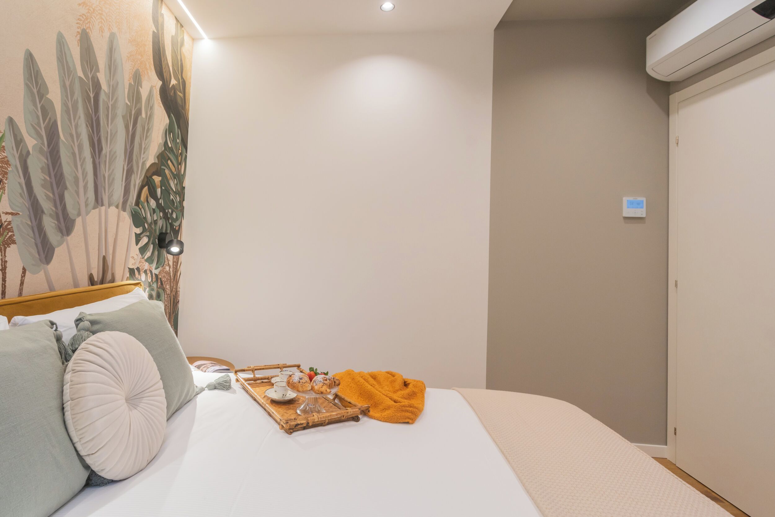 A neatly made bed with pillows, a tray with tea and snacks, and a warm blanket.