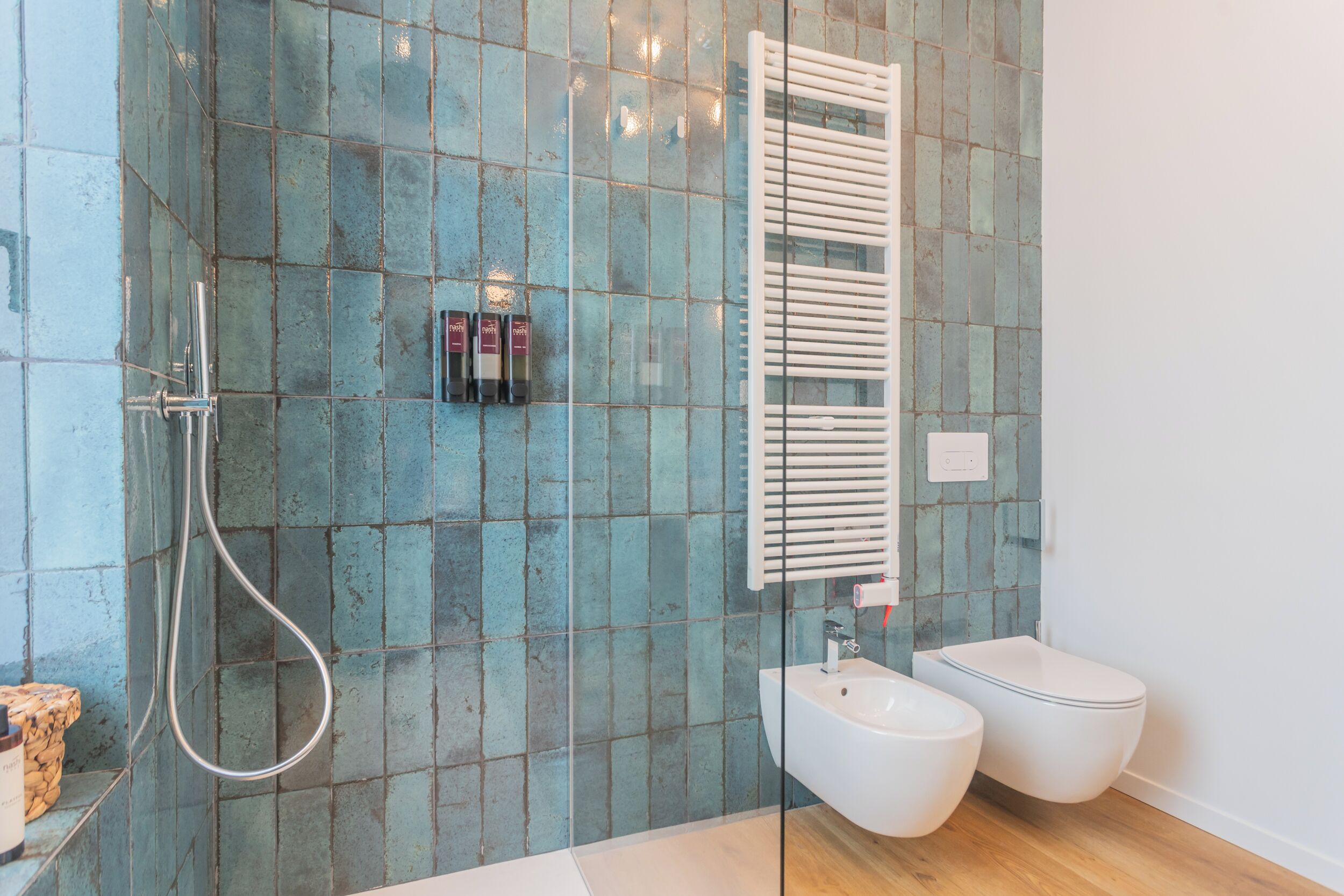 A modern bathroom with a shower, bidet, and a tiled wall.