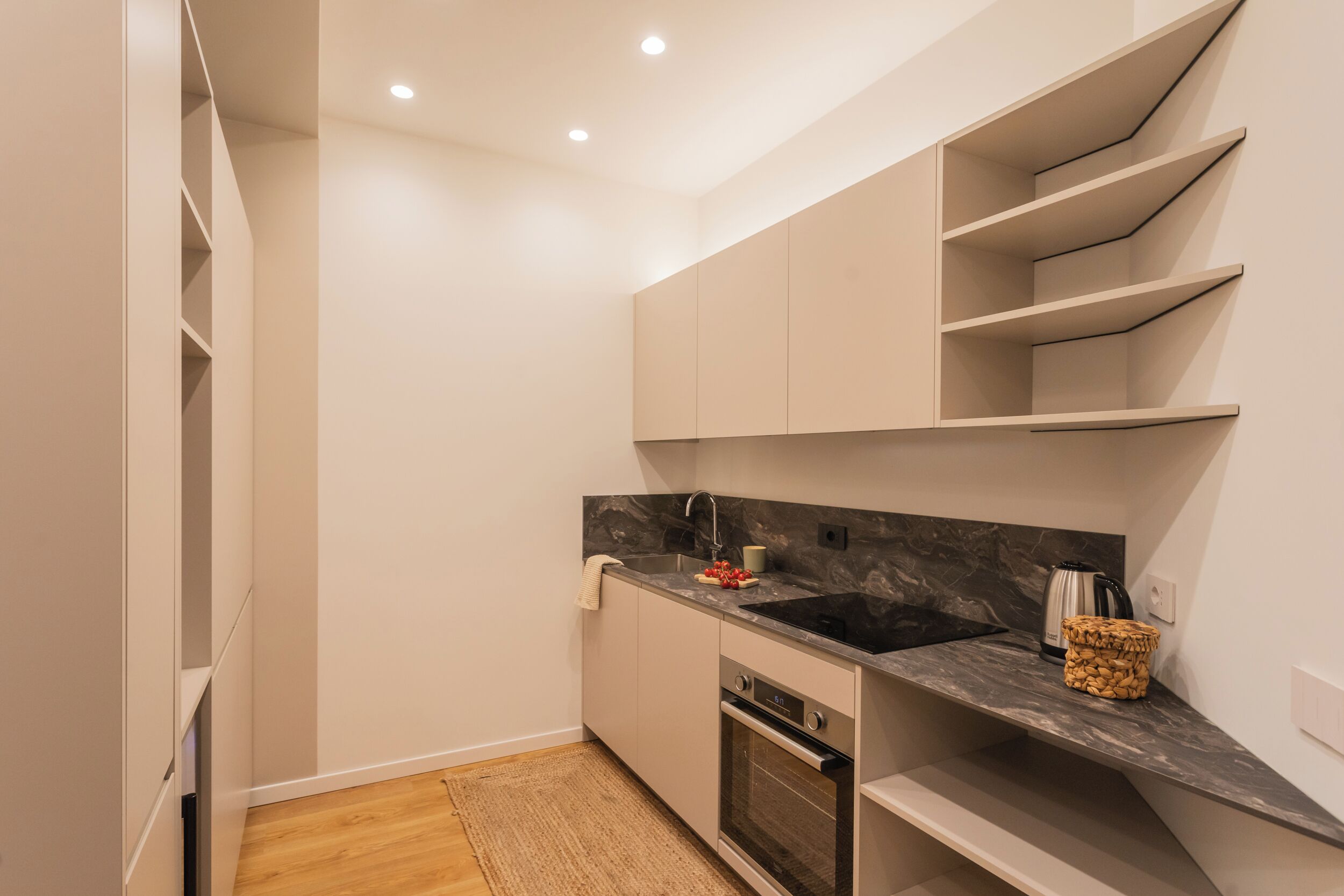 A modern kitchen with white cabinetry, a black countertop, and a built-in oven.