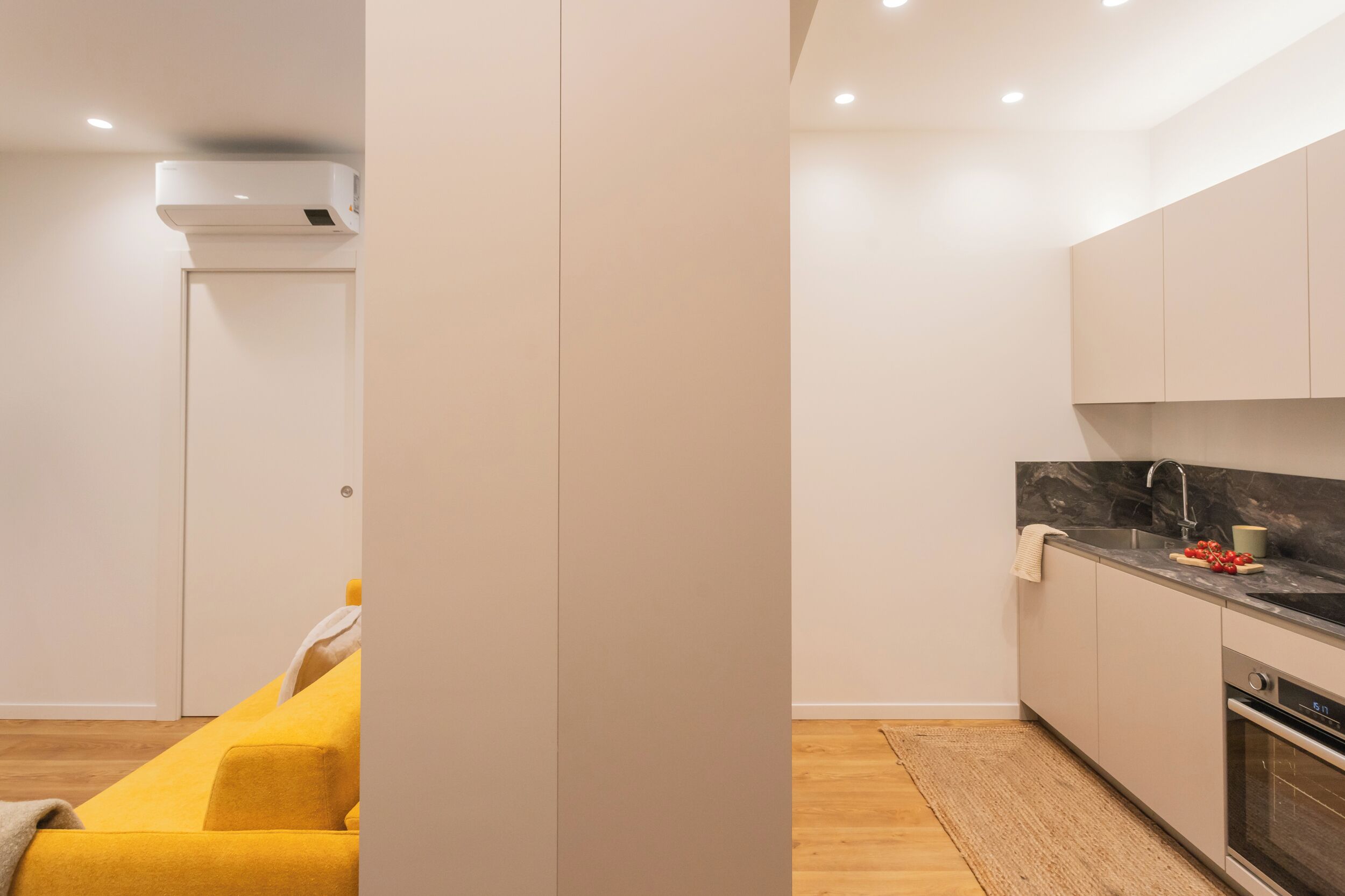 A modern kitchen with white cabinets, a marble countertop, and a built-in oven.