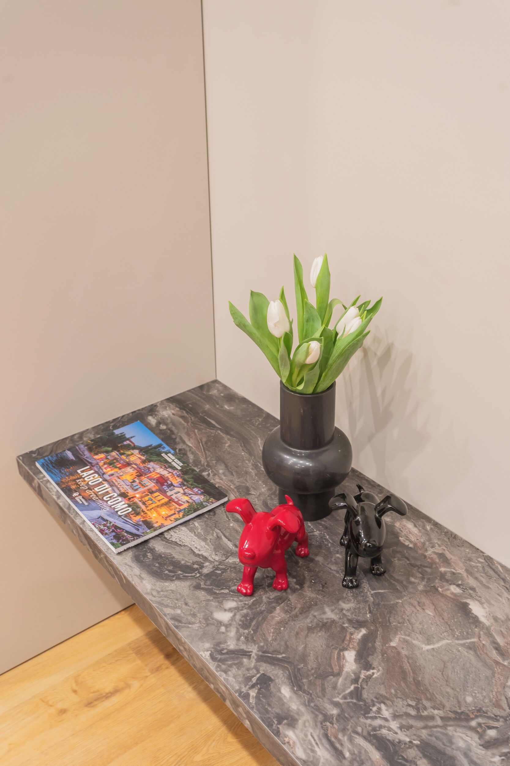 En bänkskiva av marmor med ett tidningsnummer, en vas med vita tulpaner och två djurfigurer.