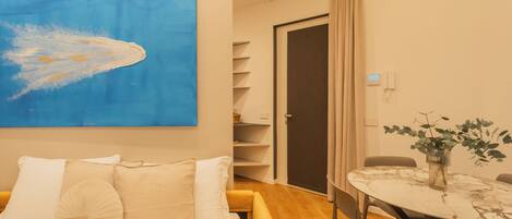A hotel room with a bed, a dining table, and a large abstract painting on the wall.