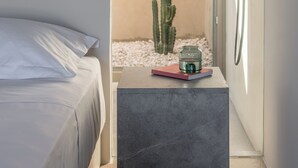 Un baño moderno con una cama, una mesita pequeña con un vaso y un cactus.