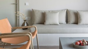 Una sala de estar moderna con un sofá, dos sillones, una mesa de centro y una lámpara fijada a la pared.