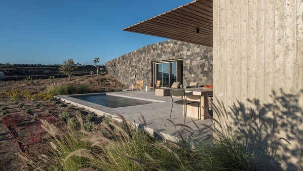Una casa moderna con fachada de piedra, una piscina y zona de estar al aire libre.