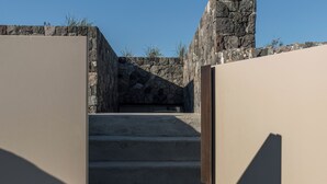Una escalera de hormigón que sube hacia un muro de piedra.