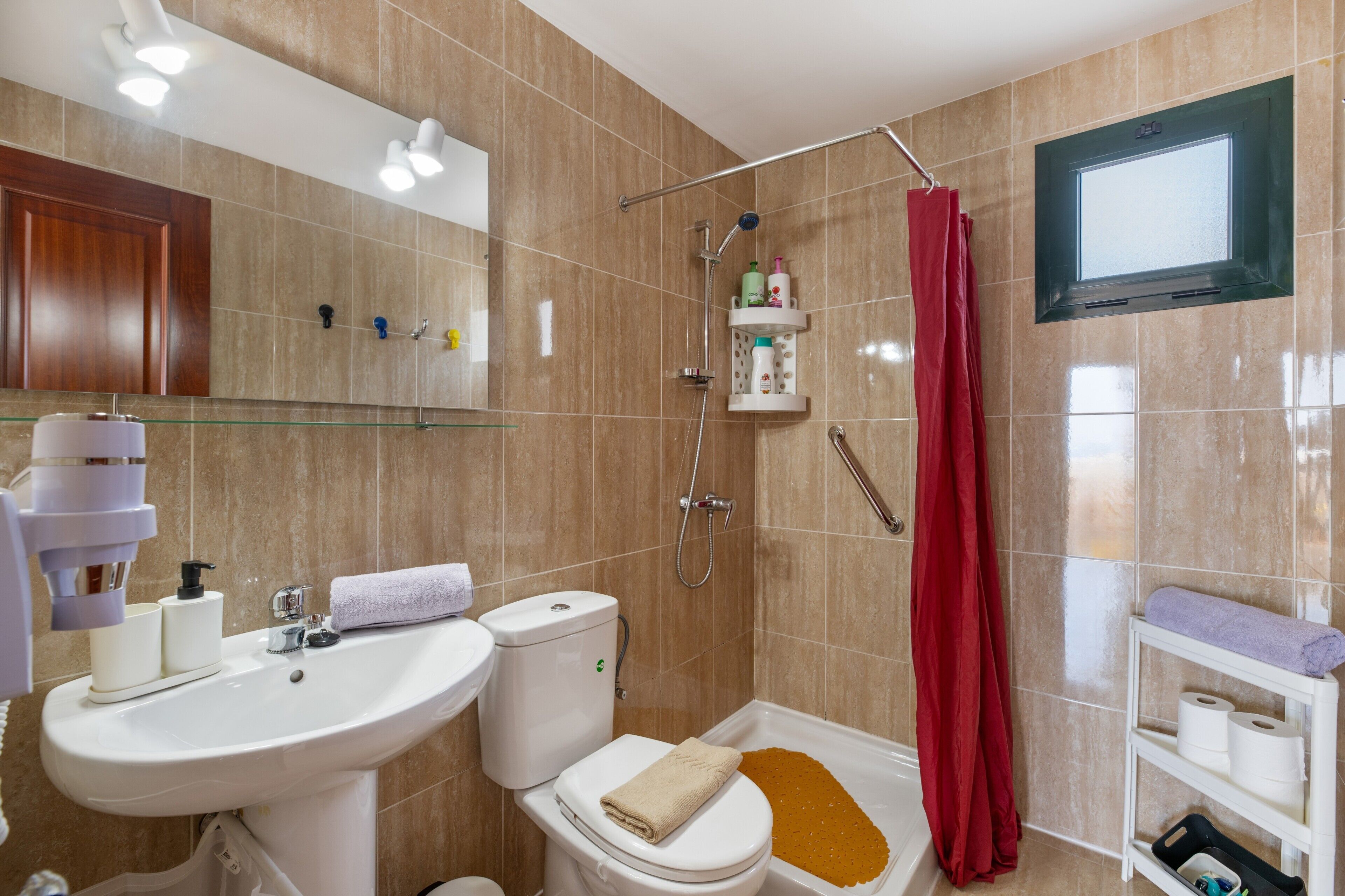 Een badkamer met een wastafel, toilet, douche en spiegel.