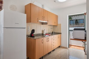 Une cuisine avec des meubles de rangement en bois, un réfrigérateur blanc, un four à micro-ondes et un évier.
