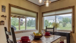 A dining area with a wooden table, red bowls, and a bowl of fruit.
