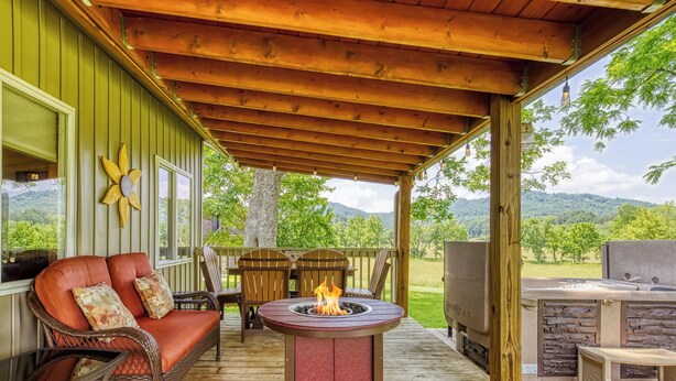 A covered outdoor patio with a fire pit, seating area, and a grill. - Valley View Farmhouse- Hot Tub, $560 Tickets per Paid Day (Sevierville)