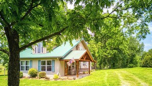 A two-story house with a green roof and a porch. - Valley View Farmhouse- Hot Tub, $560 Tickets per Paid Day (Sevierville)