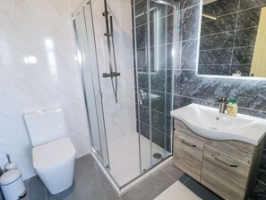 A modern bathroom with a glass-enclosed shower, a white toilet, and a vanity with a mirror. - Number 6 Villa - The View (Bunbeg)