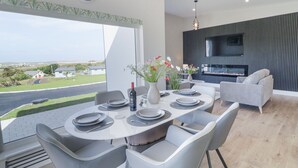 Un espace repas moderne avec vue sur la mer, une cheminée et un téléviseur.