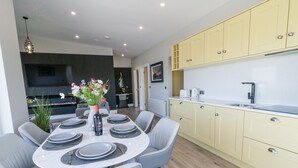 Une cuisine moderne avec des meubles de couleur jaune, un plan de travail blanc et un coin repas comprenant des chaises grises et une table ronde prévue pour quatre personnes.