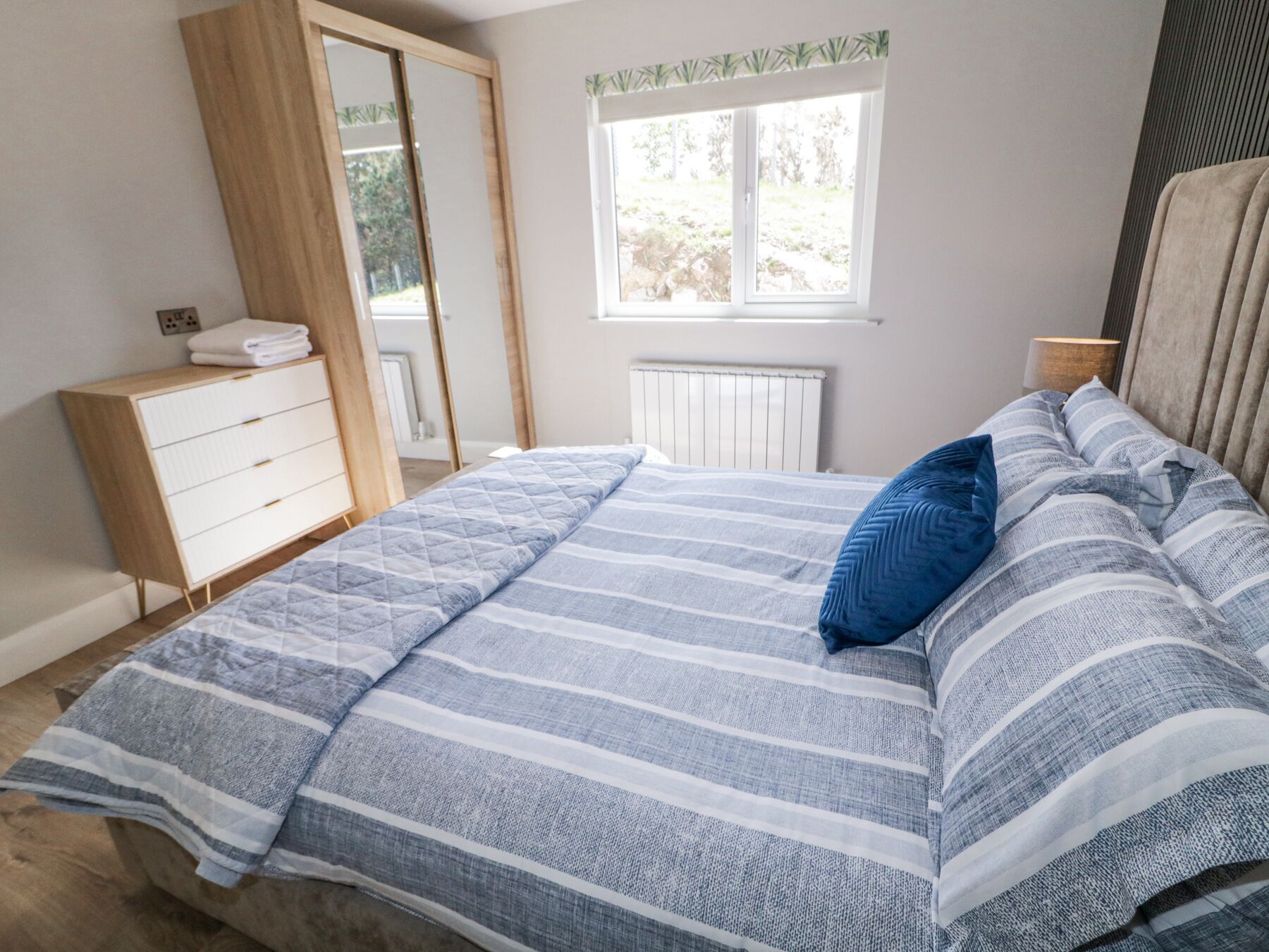 A bedroom with a bed, a dresser, a window, and a radiator.