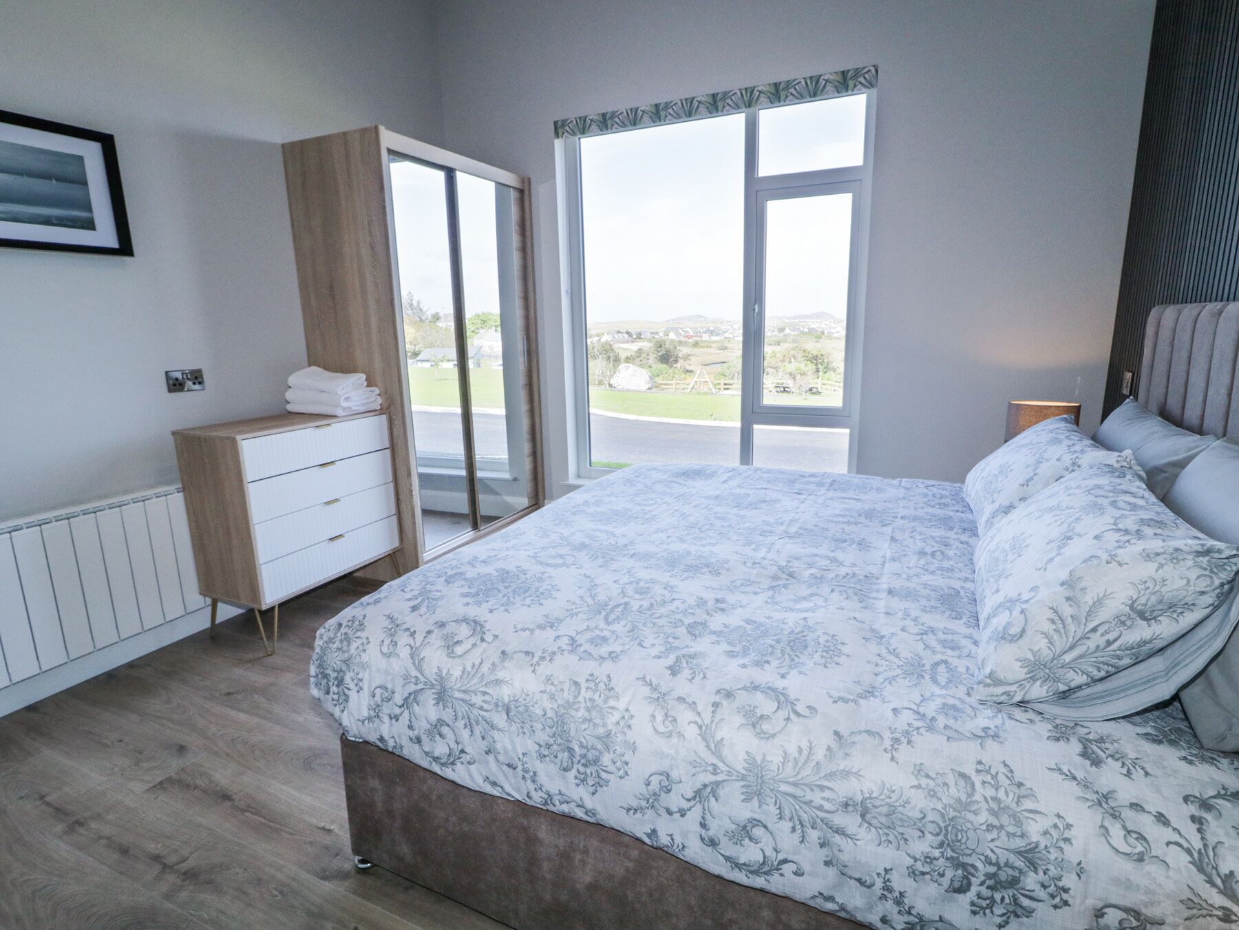 Un dormitorio con una cama grande, un armario, un aparador y una ventana con vistas al exterior.