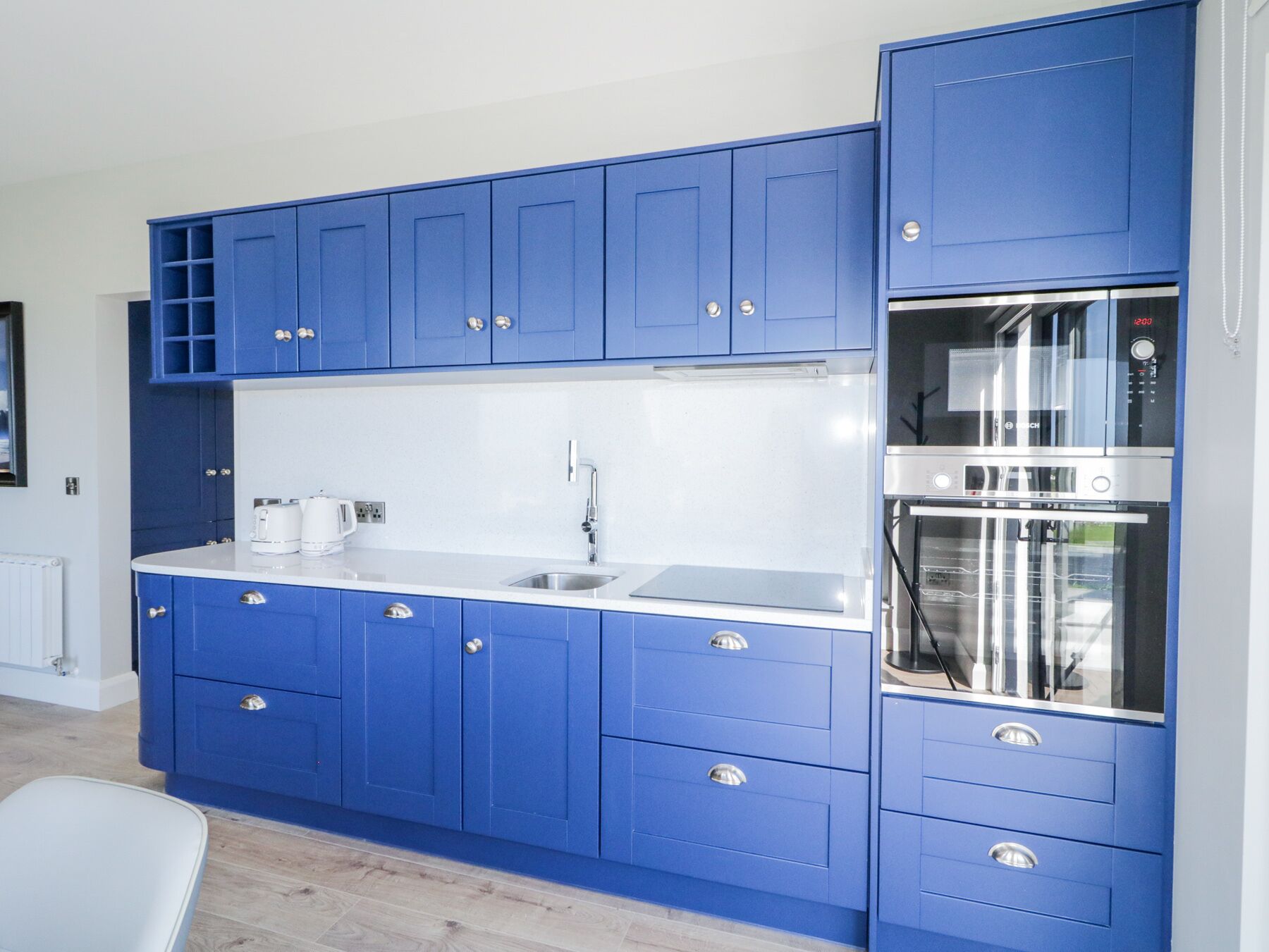 Une cuisine moderne avec des meubles bleus, un évier en acier inoxydable et un four Bosch.