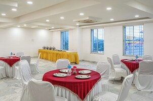 Un salón de conferencias con mesas redondas, sillas blancas y mantel amarillo.