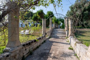 A stone pathway leading to a structure with arches, surrounded by greenery and a clear sky. - Villa 'Il Giardino Dei Gelsi' with Private Terrace, Wi-Fi and Air Conditioning (Otranto)
