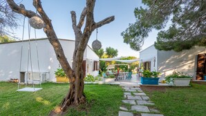Un patio con mobiliario exterior, una mecedora y un árbol.