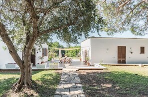 Un bâtiment blanc avec un chemin de pierre menant à un patio aménagé avec du mobilier d’extérieur.