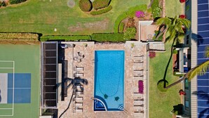 Eine Vogelperspektive eines Resorts mit Swimmingpool, Liegestühlen, Tennisplatz und einer Solaranlage.