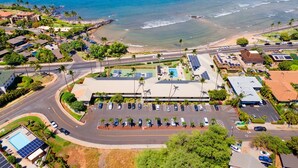 Luftaufnahme einer Küstenlandschaft mit Parkplatz, Gebäuden und Strand.