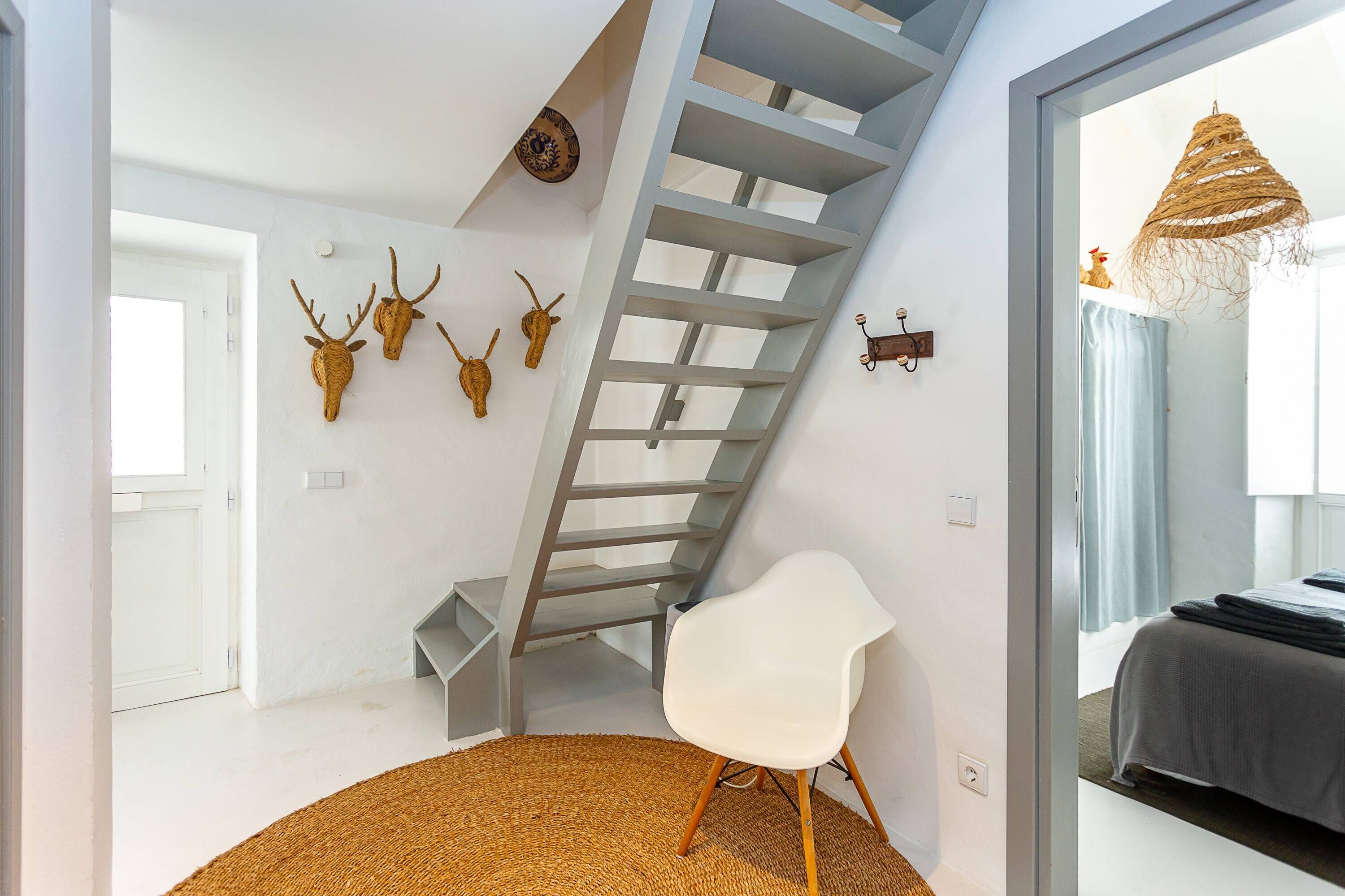 A modern room with a staircase, a white chair, and decorative antler heads on the wall.