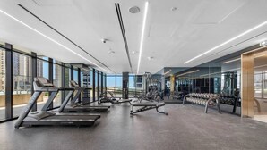 A modern gym with treadmills, elliptical machines, and weight stations. - Missoni | Canal View | Fully Furnished Studio (Dubai)