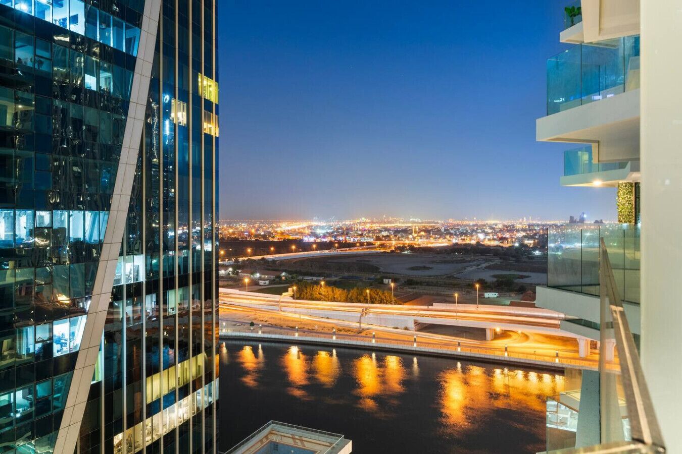 Ein Hochhaus mit Blick auf eine Skyline und einen Fluss mit beleuchteten Brücken bei Nacht.
