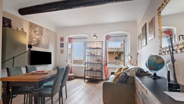 A modern living room with a wooden dining table, chairs, a sofa, a TV, a bookshelf, and a globe. - Apartment 'Giada's Retreat' with Sea View, Wi-Fi and Air Conditioning (Genova)