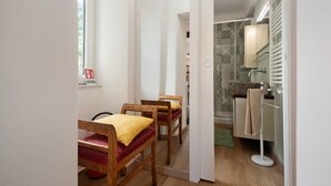 A room with a bed, a chair, a mirror, and a bathroom with a towel rack. - Apartment 'Giada's Retreat' with Sea View, Wi-Fi and Air Conditioning (Genova)