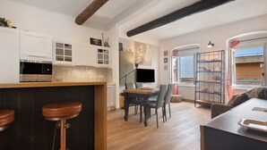 A kitchen with wooden stools, a dining table, and a TV. - Apartment 'Giada's Retreat' with Sea View, Wi-Fi and Air Conditioning (Genova)