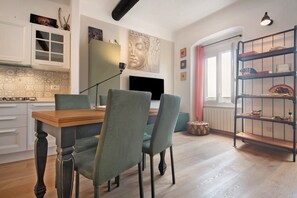 Un comedor con una mesa de madera y cuatro sillas, un televisor y una estantería con objetos decorativos.