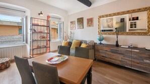 A living room with a wooden dining table, a sofa with cushions, a bookshelf, and a large mirror with a decorative frame. - Apartment 'Giada's Retreat' with Sea View, Wi-Fi and Air Conditioning (Genova)