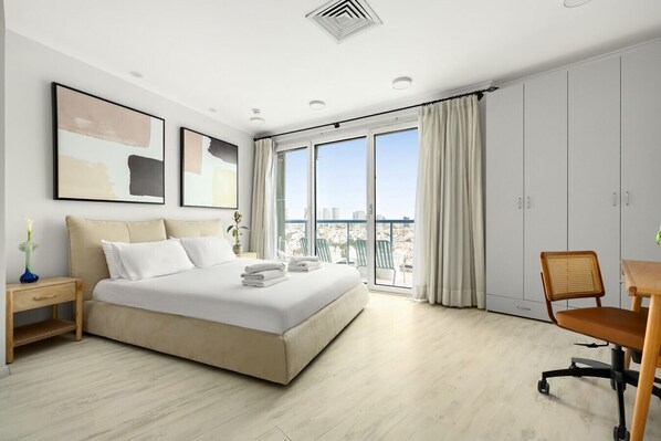 Una habitación de hotel moderna con una cama grande, un escritorio y un balcón con vistas a la ciudad.