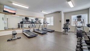 Une salle de sport équipée de tapis de course, d’un vélo d’appartement et d’haltères.