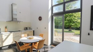 Una cocina moderna con zona de comedor, ventanas amplias y vistas al exterior.