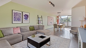 A modern living room with a grey sofa, a coffee table, and artwork on the walls. - Spacious 3 bedroom apartment with parking (Machelen)