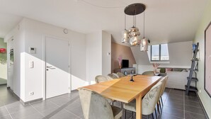 A modern dining area with a wooden table and chairs, a built-in bench, and pendant lighting. - Spacious 3 bedroom apartment with parking (Machelen)