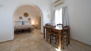 Une pièce comprenant une table à manger, des chaises, un banc, une porte en arc de cercle et un appareil de climatisation.