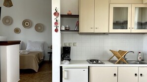 Eine kleine Küche mit Kühlschrank, Kaffeemaschine und Spüle mit Geschirrständer.