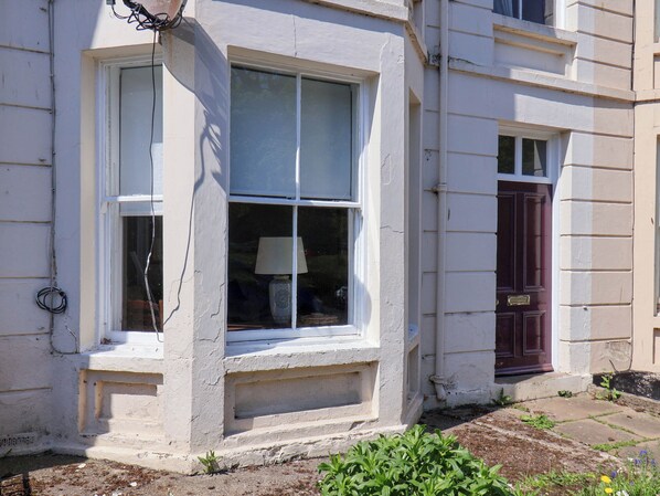 A building with a white window, a dark door, and a small garden area. - Flat 1 (Scarborough)
