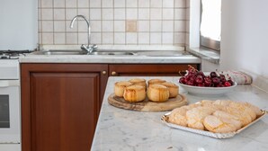 A kitchen with a marble countertop, wooden cabinets, a sink, and a wooden cutting board with pastries. - Holiday Home 'Santa Caterina' with Mountain View, Wi-Fi and Air Conditioning (Santa Caterina di Pittinuri)