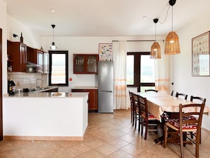 Une cuisine dotée d’un îlot central, de meubles en bois, d’un réfrigérateur et d’un coin repas avec une table et des chaises.